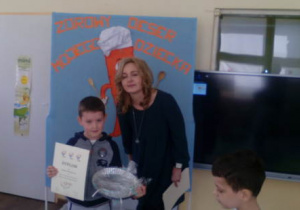 Chłopiec odbiera nagrodę, pozując do zdjęcia wraz z Panią dyrektor.
